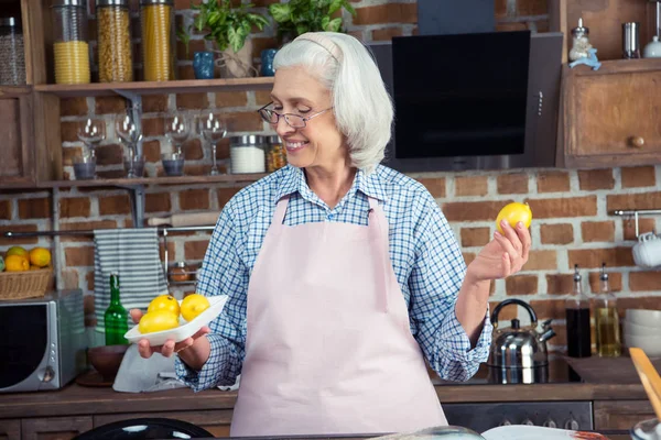 Femme regardant les citrons dans la cuisine — Photo de stock