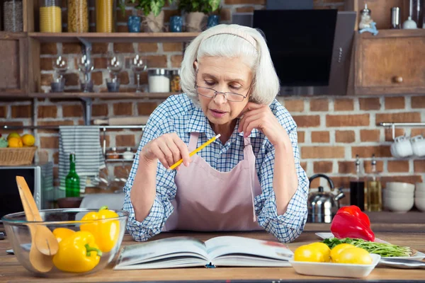 Mulher sênior com livro de receitas — Fotografia de Stock