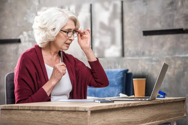 Старша жінка регулює окуляри — стокове фото