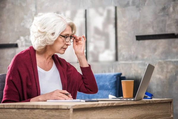 Senior woman adjusting eyeglasses — Stock Photo