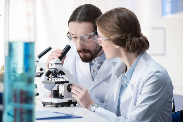 Químicos trabajando con microscopio - foto de stock