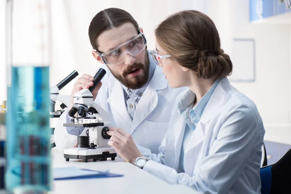 Químicos trabajando con microscopio - foto de stock