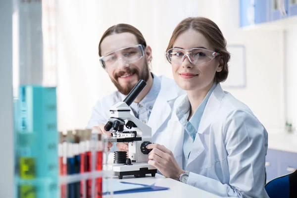 Químicos trabajando con microscopio - foto de stock