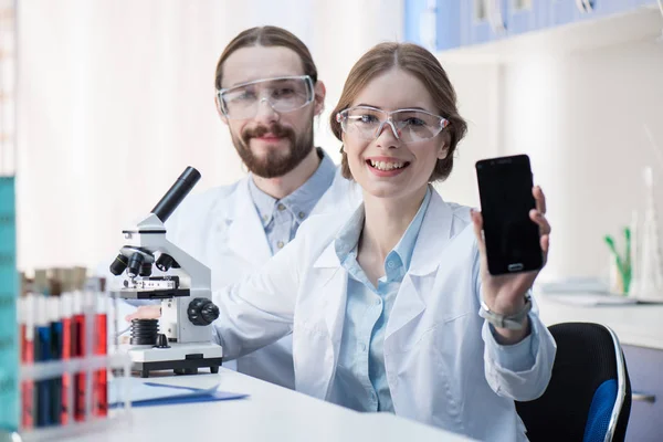 Female scientist showing smartphone — Stock Photo