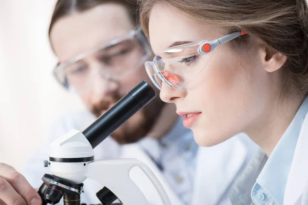 Químicos trabajando con microscopio - foto de stock