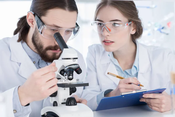 Chemists working with microscope — Stock Photo