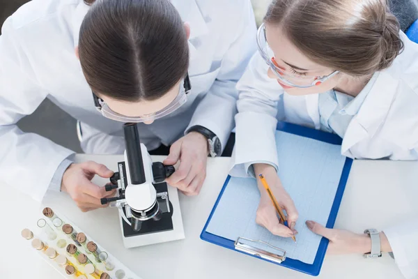 Chemists working with microscope — Stock Photo