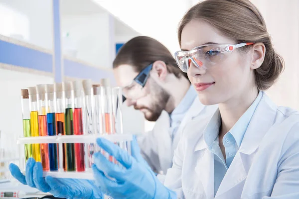 Scientist looking on test tubes — Stock Photo
