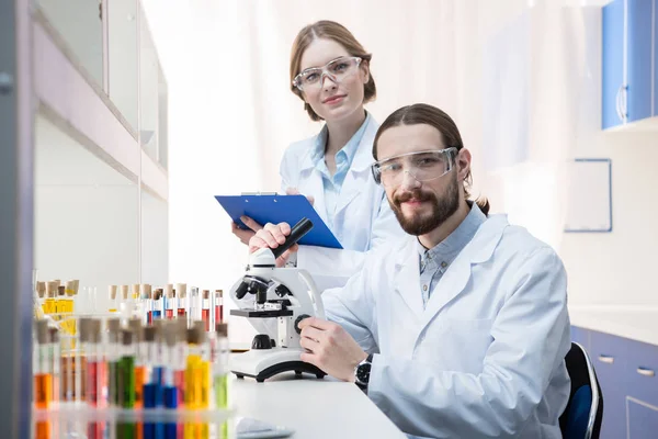 Químicos trabajando con microscopio - foto de stock