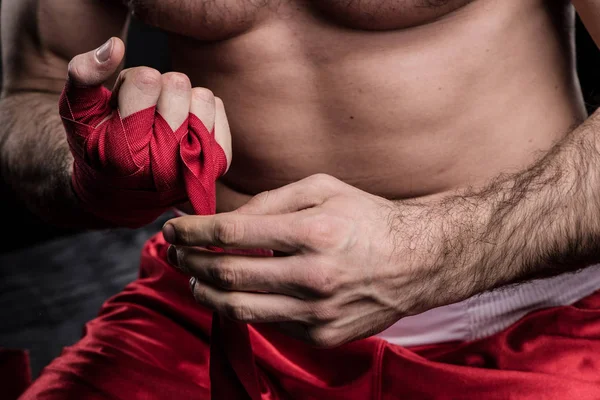 Sportsman wrapping hand in boxing bandage — Stock Photo