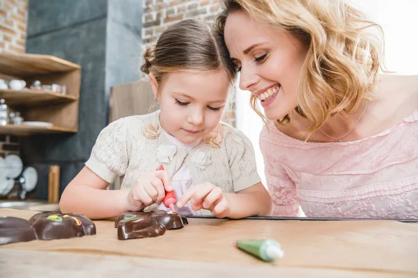 Mutter und Tochter beim Zuckerguss von Schokohasen — Stockfoto