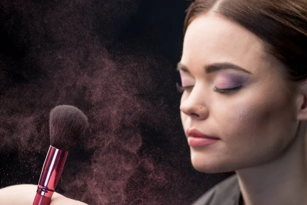 Make-up artist sprinkling face of model — Stock Photo