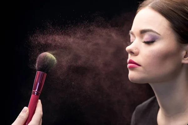 Make-up artist sprinkling face of model — Stock Photo