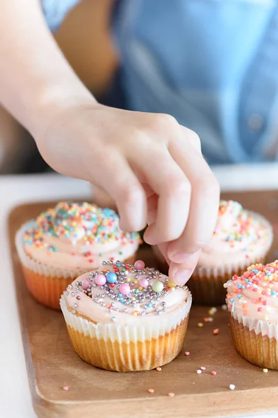 Mädchen legt Konfetti auf Cupcakes — Stockfoto