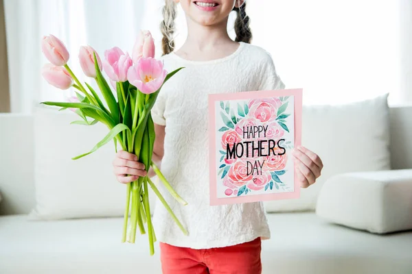 Girl holding postcard and tulips — Stock Photo