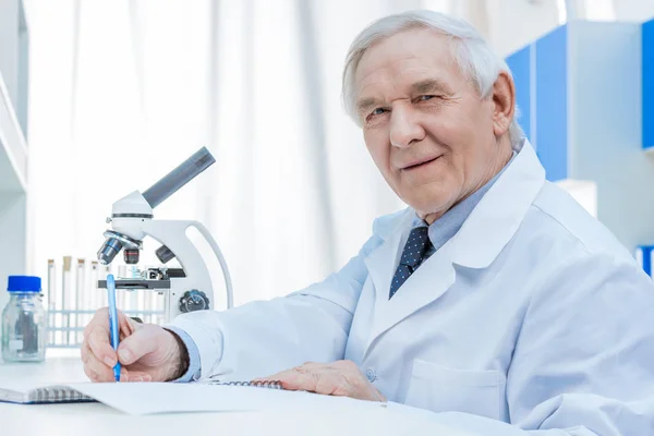 Senior chemists writing in notepad — Stock Photo