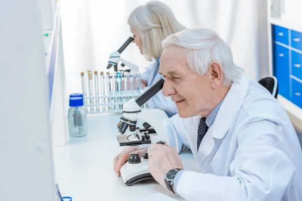Senior chemists with microscope — Stock Photo