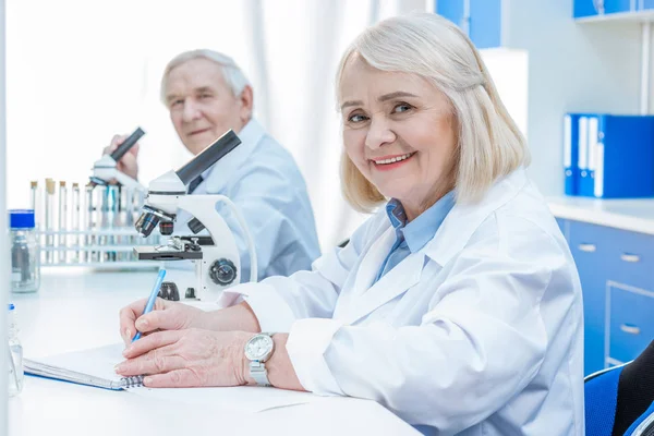 Senior chemists writing notes — Stock Photo