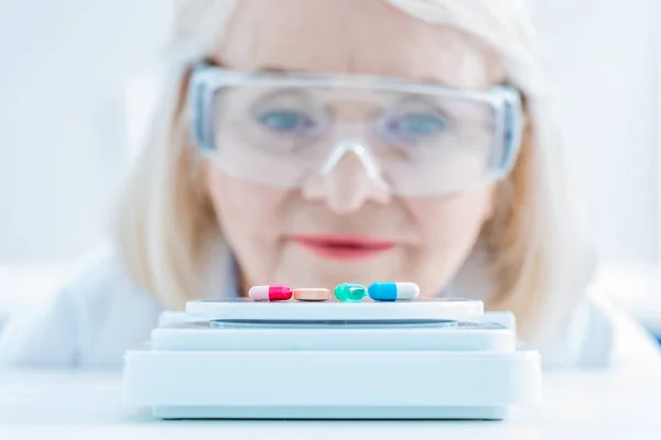 Senior scientist looking at pills — Stock Photo