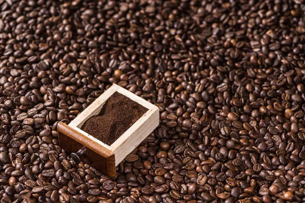 Ground coffee on coffee beans — Stock Photo