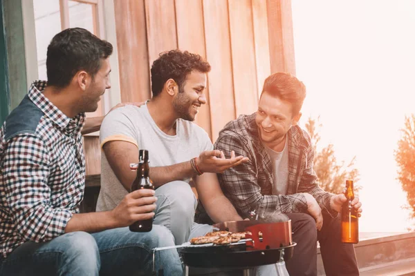 Amigos bebendo cerveja e fazendo churrasco — Fotografia de Stock