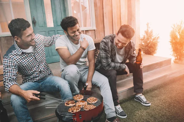 Friends drinking beer and making barbecue — Stock Photo