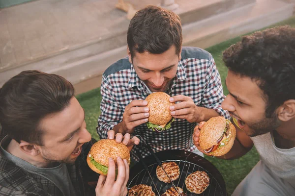 Hommes mangeant des hamburgers — Photo de stock