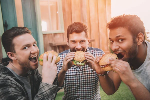 Hommes mangeant des hamburgers — Photo de stock