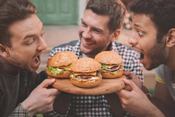 Uomini che mangiano hamburger — Foto stock
