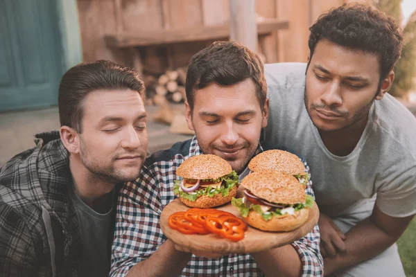Hombres comiendo hamburguesas - foto de stock