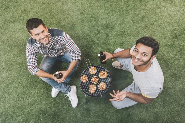 Friends drinking beer and making barbecue — Stock Photo