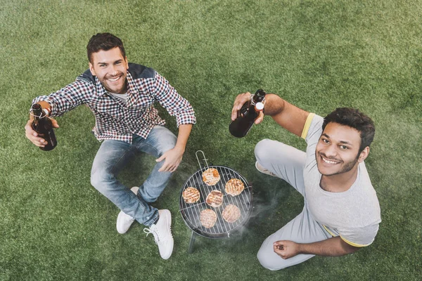 Amigos bebendo cerveja e fazendo churrasco — Fotografia de Stock