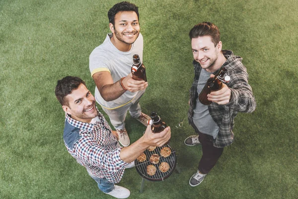 Amigos bebiendo cerveza y haciendo barbacoa - foto de stock