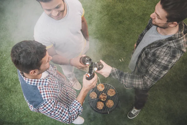 Amigos bebendo cerveja e fazendo churrasco — Fotografia de Stock