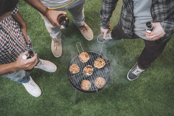 Amigos bebiendo cerveza y haciendo barbacoa - foto de stock