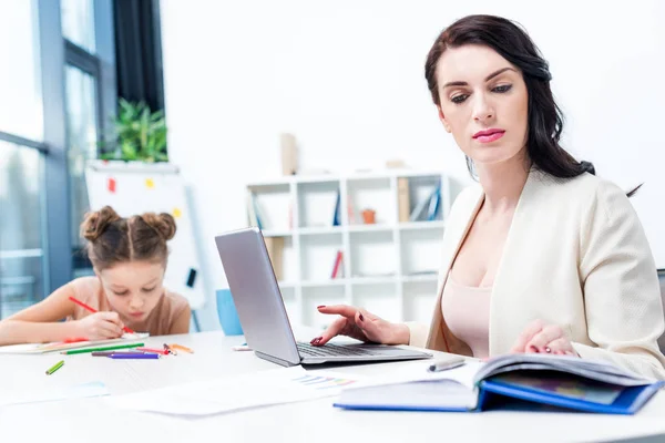 Business woman working while daughter drawing — стоковое фото