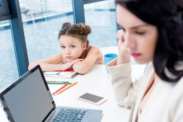 Femme d'affaires travaillant alors que sa fille dessin — Photo de stock