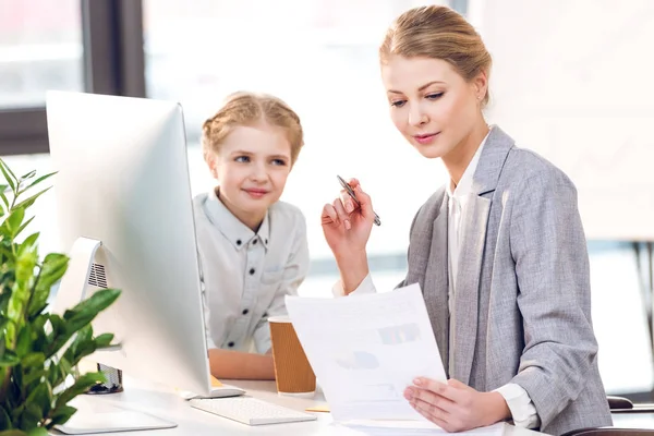 Mujer de negocios con hija trabajando en la oficina - foto de stock