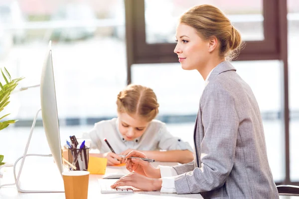 Mother working while daughter drawing — Stock Photo