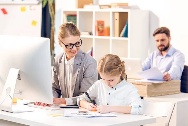 Madre trabajando mientras hija dibujo - foto de stock