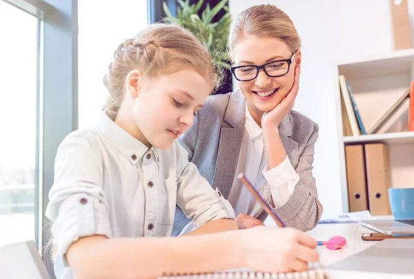 Daughter drawing with mother in office — Stock Photo