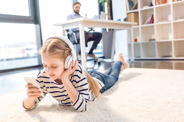 Fille utilisant smartphone et écouteurs — Photo de stock