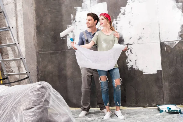 Couple with schemes and paint roller — Stock Photo