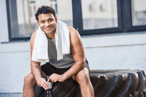 Uomo con bottiglia d'acqua a riposo in palestra — Foto stock