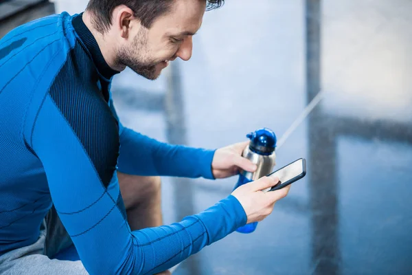 Mann benutzt Smartphone im Fitnessstudio — Stockfoto