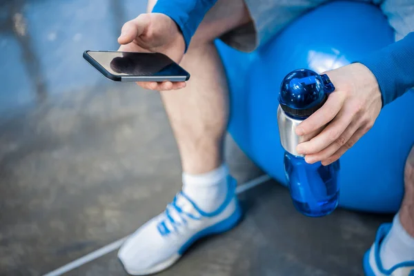 Mann benutzt Smartphone im Fitnessstudio — Stockfoto
