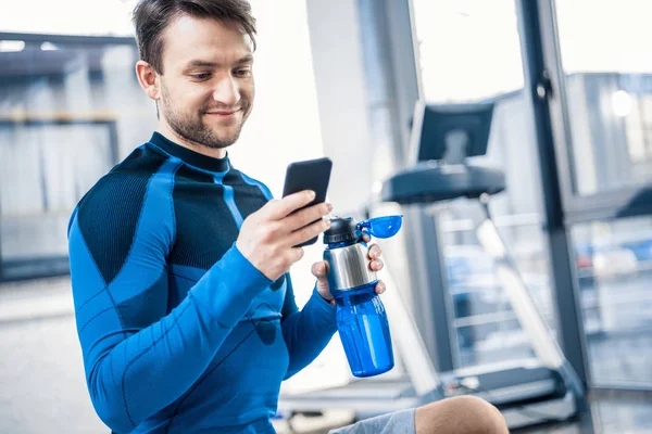 Людина використовує смартфон у спортзалі — стокове фото