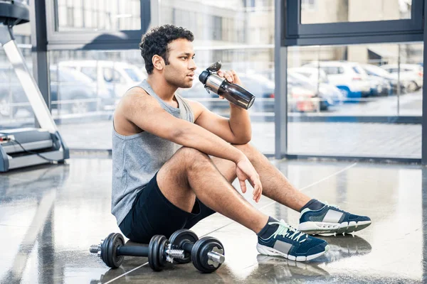 Uomo con bottiglia d'acqua a riposo in palestra — Foto stock