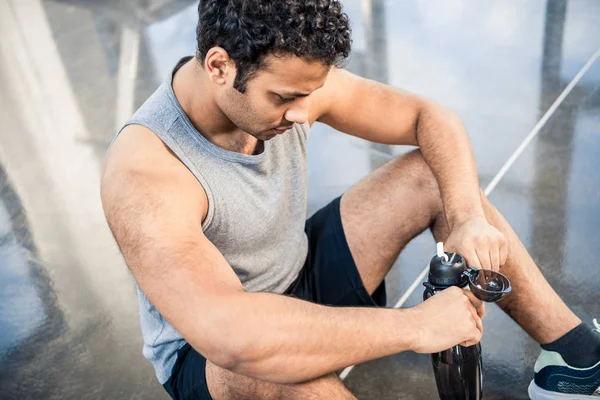 Uomo con bottiglia d'acqua a riposo in palestra — Foto stock