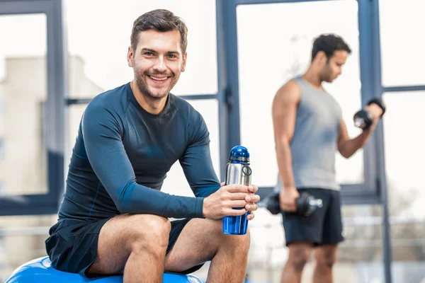 Homme avec bouteille d'eau reposant à la salle de gym — Photo de stock
